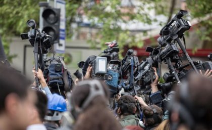 A large group of journalists and camera operators filming event. Image, Adobe. 